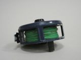 a spool of green thread on a white surface