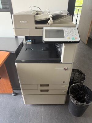 une imprimante posée sur un bureau, à côté d'une poubelle
