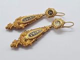 deux paires de boucles d'oreilles en or et émail noir sur un fond blanc