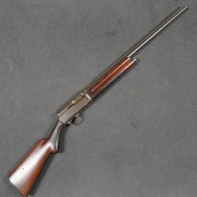 un fusil avec une crosse et un canon en bois, posé sur une surface grise