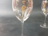 two wine glasses with gold designs on them on a table
