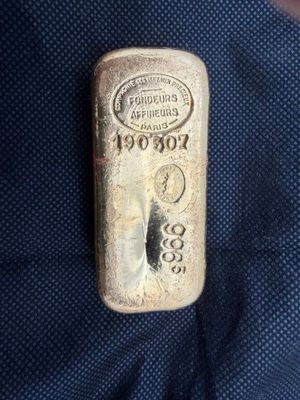un vieux lingot d'argent posé sur un tissu bleu