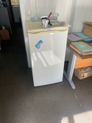 un petit réfrigérateur blanc dans le coin d'une pièce