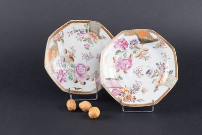 deux assiettes ornées de fleurs et de noix, posées sur un fond noir