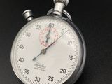 a close up of a silver stopwatch on a black surface