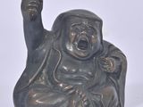 a statue of a laughing buddha sitting on a white surface