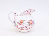 a small white pitcher with a floral design on it