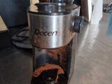 a coffee grinder sitting on top of a counter next to a cup