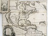 an old map of the americas with a book open on top of it