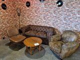 a couch, chair, and table in a room with a brick wall