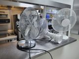 two fans that are sitting on a counter in a kitchen