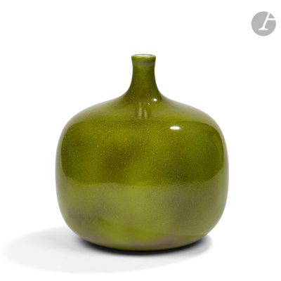un vase vert posé sur une surface blanche