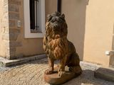 a statue of a lion sitting on a stone block in front of a building