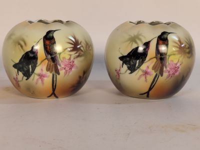 deux vases avec des oiseaux peints assis sur une table