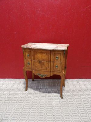 an old wooden chest of drawers with marble top against a red wall