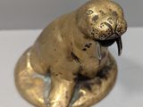 une statuette en forme de sceau doré posée sur une table blanche