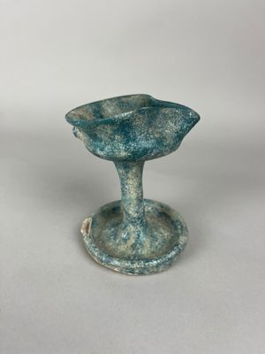 a close up of a small blue vase on a white surface