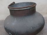 a large black pot sitting on the ground near a wall