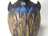 a blue and brown vase sitting on a white surface