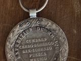 une médaille d'argent posée sur une table en bois, avec un porte-clés accroché dessus