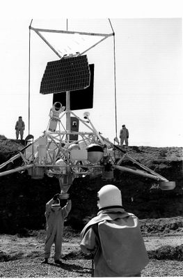photographie en noir et blanc d'un homme debout devant un rover spatial