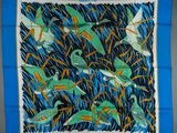a blue square scarf with birds and grass on it