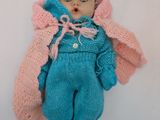 a doll that is laying down on a white surface
