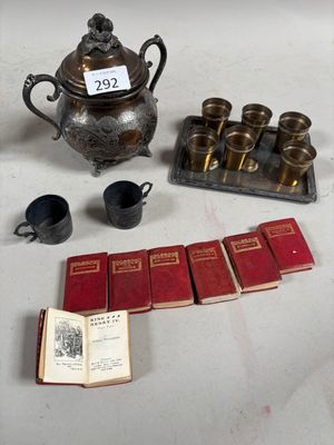 une théière en argent, un livre, des tasses et une théière posées sur une table