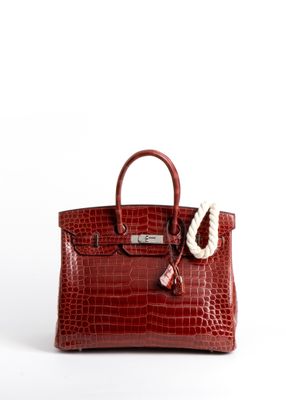 un sac à main en cuir de crocodile rouge, avec une corde blanche suspendue à la poignée