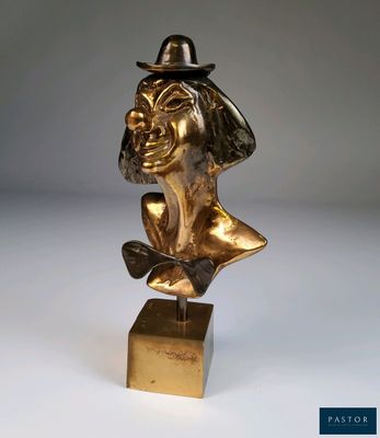 une statue en or représentant un homme portant un chapeau et un nœud papillon