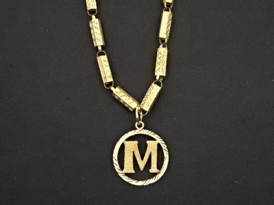 un gros plan d'un collier orné d'une lettre « m »