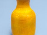 a small yellow vase sitting on a blue surface