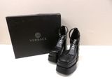 une paire de chaussures noires à talons hauts posée à côté d'une boîte noire