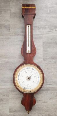 une horloge accrochée au mur, sur laquelle se trouve un baromètre