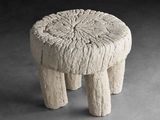 un petit tabouret en pierre posé sur une surface grise