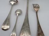 five silver spoons and a fork on a white surface