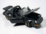 a black toy car with open doors on a white surface