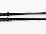 two black and gold hair brushes on a white surface