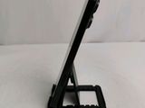 a small black cell phone on a stand on a white surface