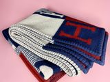 une pile de trois couvertures bleues et rouges sur un fond rose