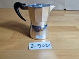 une cafetière en argent posée sur une table en bois, avec une étiquette de prix
