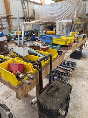 Plusieurs bacs contenant des outils sont alignés sur un établi dans un atelier.