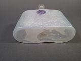 a small plastic container with a purple stone on top of it