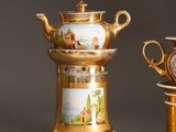 two gold vases with pictures on them sitting next to each other