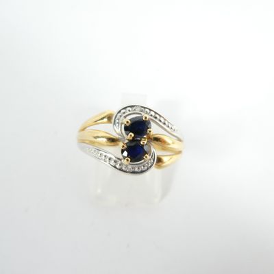 gros plan d'une bague en or avec une pierre bleue et des diamants