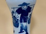 un vase bleu et blanc sur lequel est représenté un homme