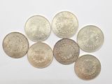 a group of six different british coins on a white surface