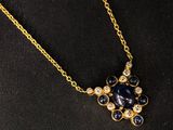 a close up of a gold necklace with blue and white stones