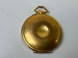 a small gold pocket watch on a white surface