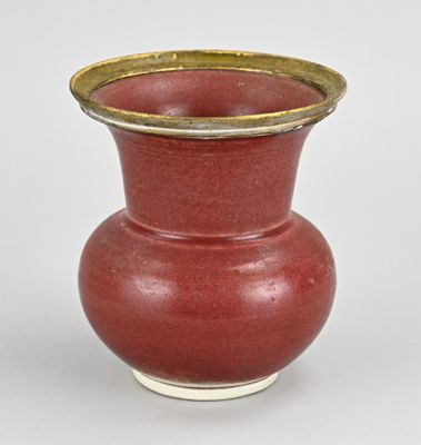 a red vase with a gold rim sitting on a white surface